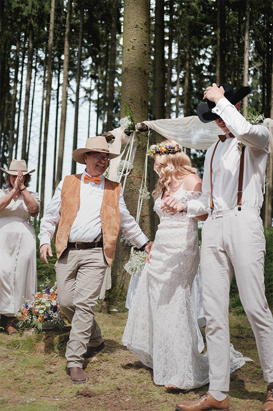 Hochzeitspaar nach der Trauung begleitet vom Priester